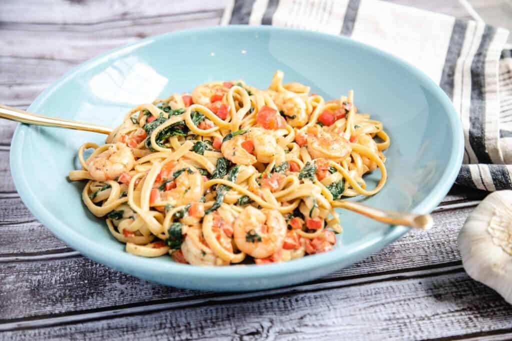 This is a bowl of creamy spinach, red pepper, and shrimp pasta. 