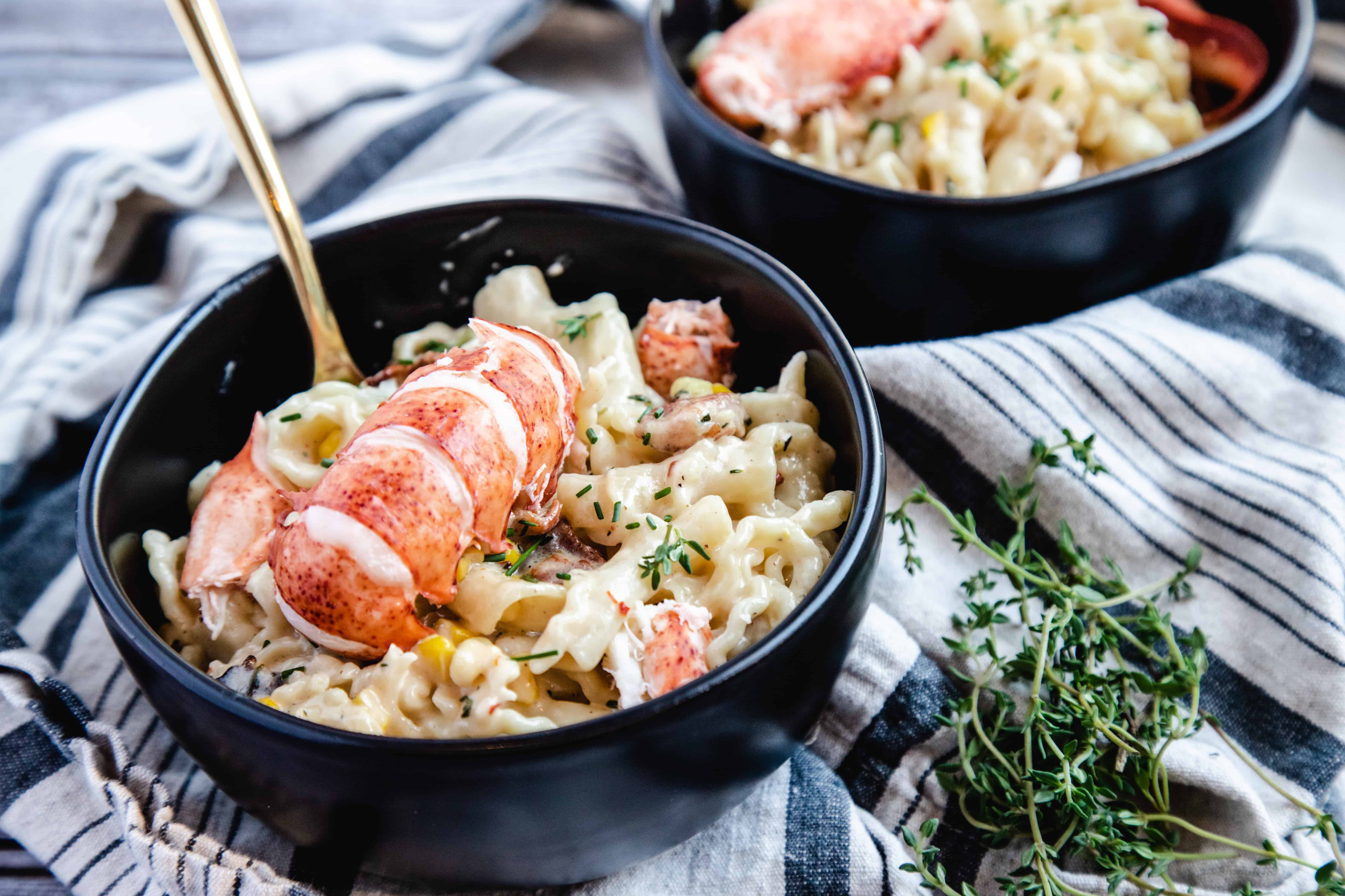 This is a picture of a bowl of lobster mac and cheese with thyme on the side. 