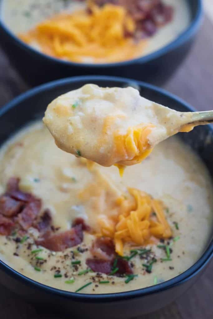 This is a picture of cauliflower and baked potato soup on a spoon.