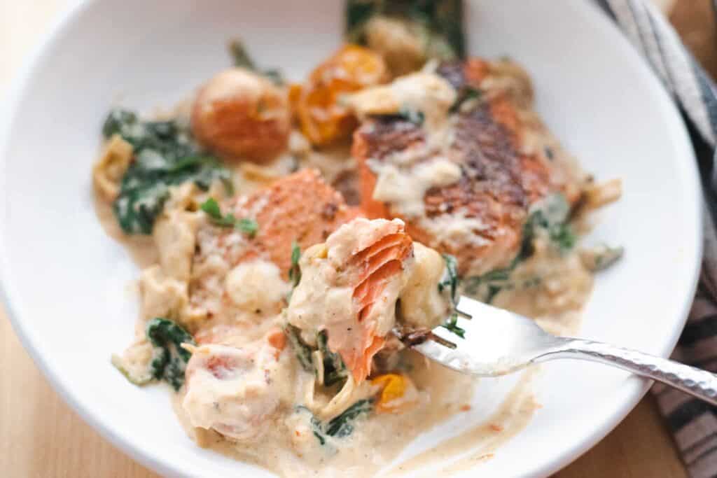 This is a picture of spinach and artichoke salmon on a fork.