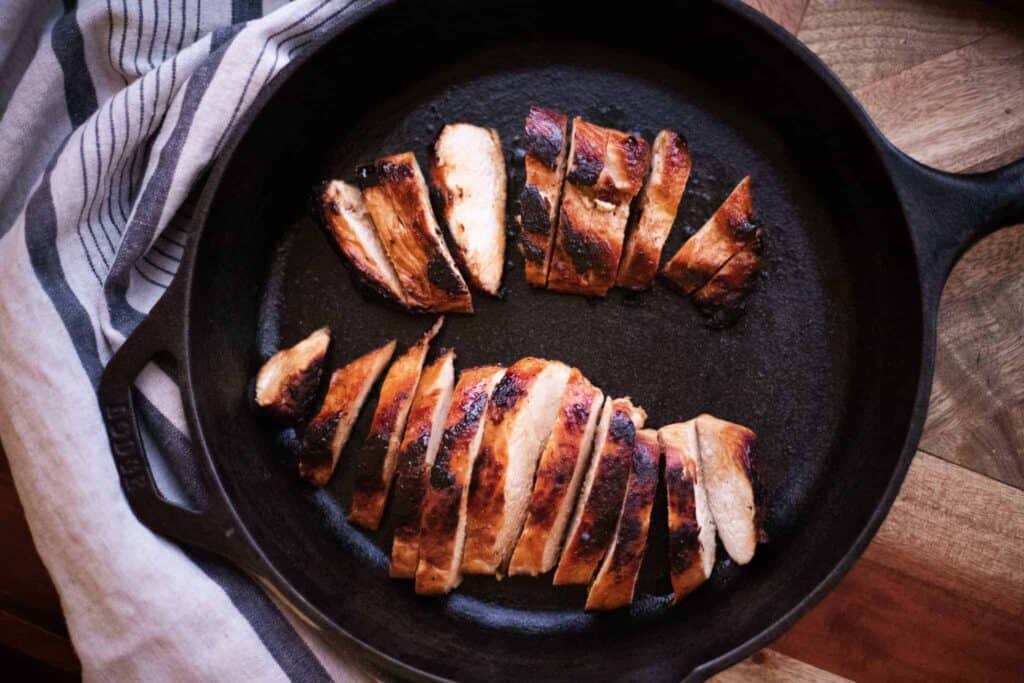 This is a picture of two marinated pan-seared chicken breasts in a pan.