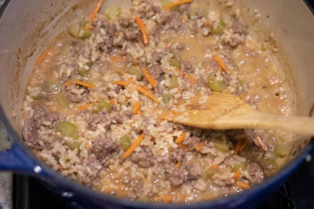 This is a picture of rice and meat cooking in a pot making cheeseburger soup.