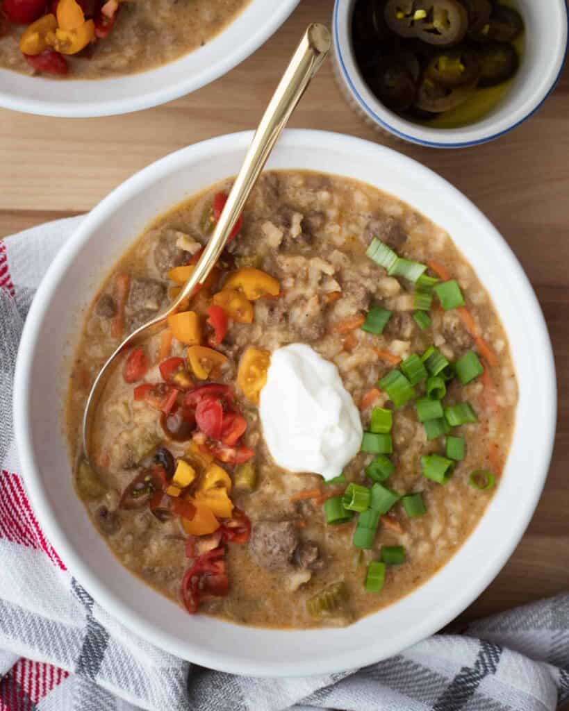 This is a picture of cheeseburger soup with sour cream and a spoon.