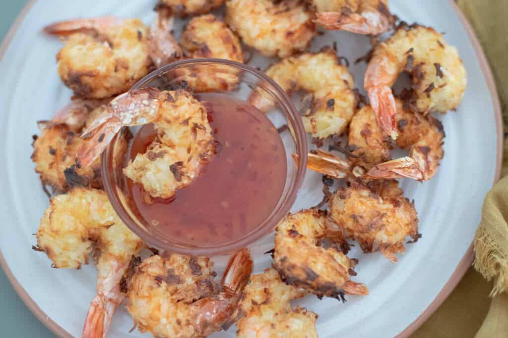 This is a picture of coconut shrimp on a plate with dipping sauce. The Hangry Economist.
