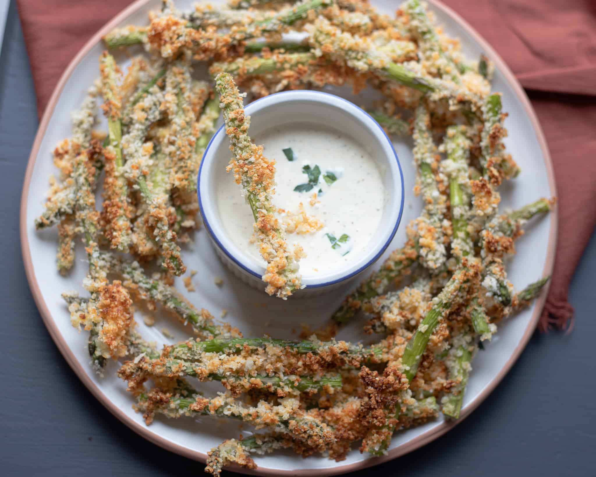 Asparagus fries on a plate with lemon dijon aioli in a bowl. The Hangry Economist.
