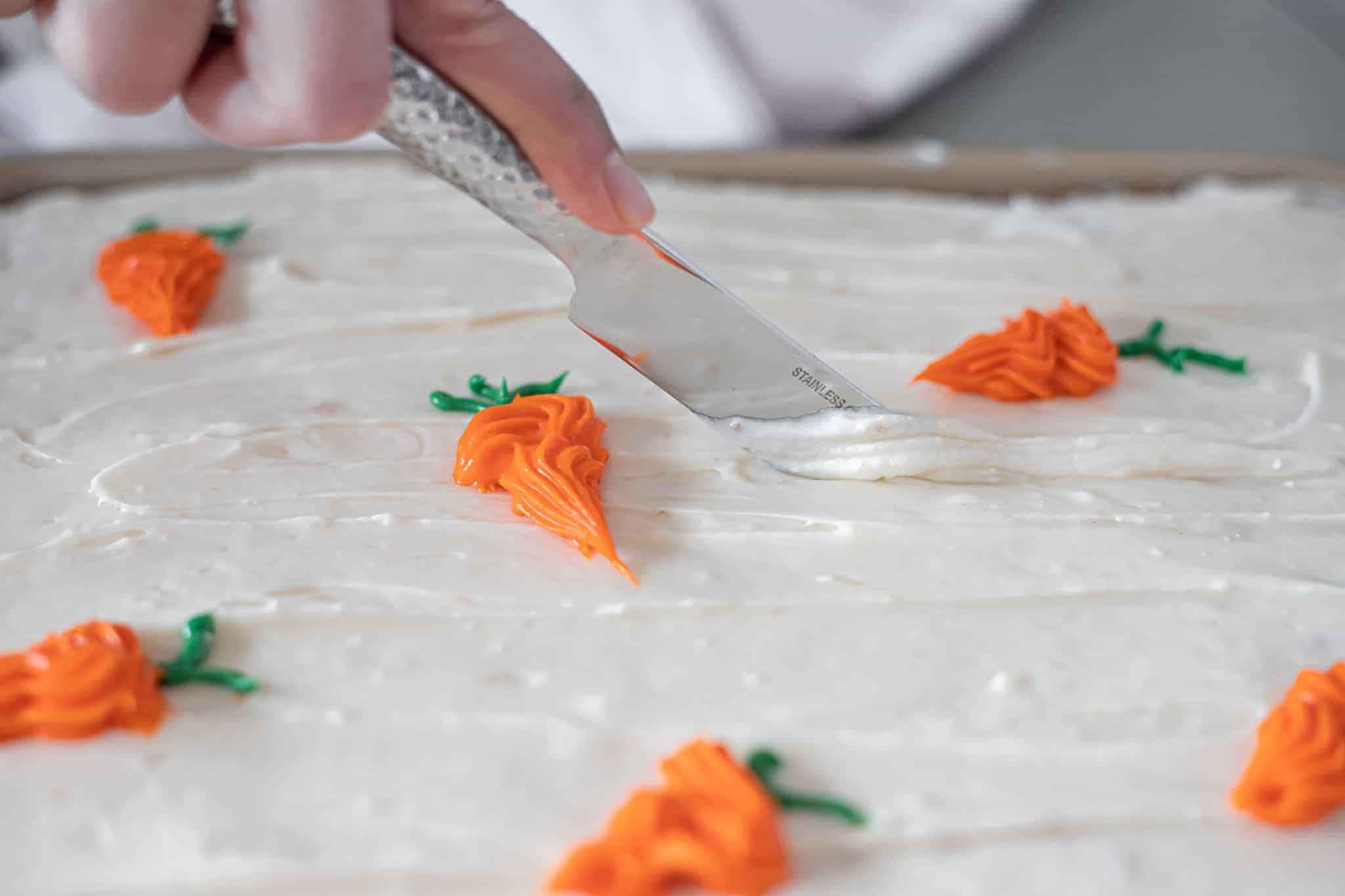 This is a picture of sheet pan carrot cake being cut with a butter knife. The Hangry Economist.