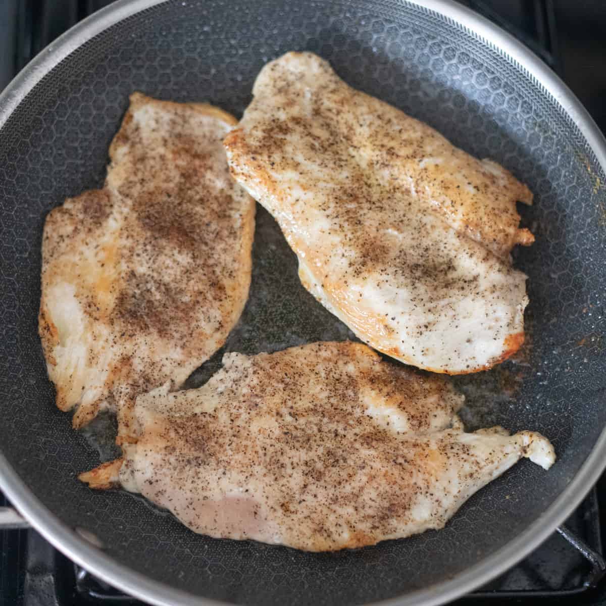 Chicken breasts cooking in a pan. 