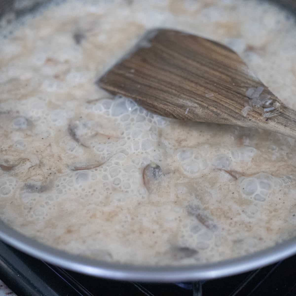 A wine and coconut cream sauce simmering in a pan. 