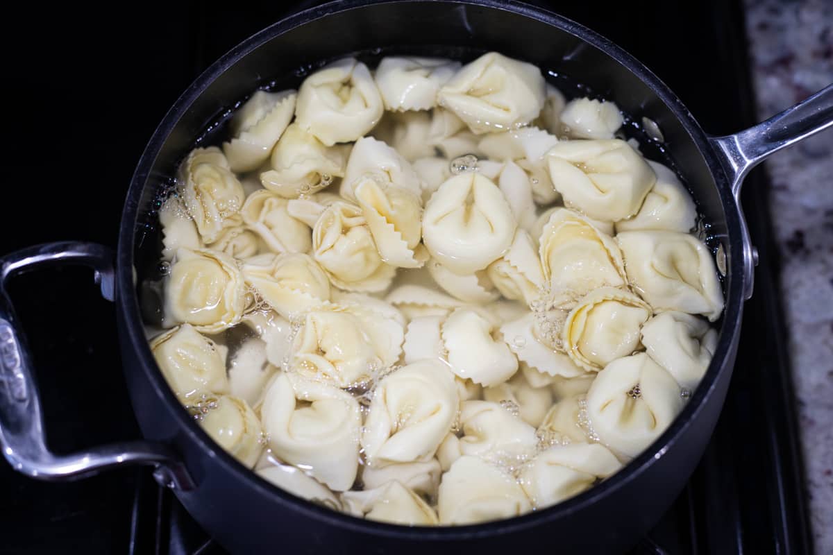 Cheese tortellini cooking in a pot of water. 