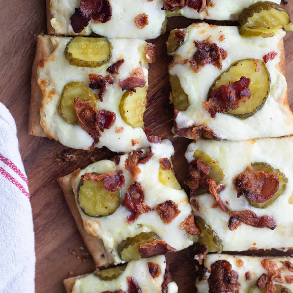 Pickle flatbread pizza cut into square slices.