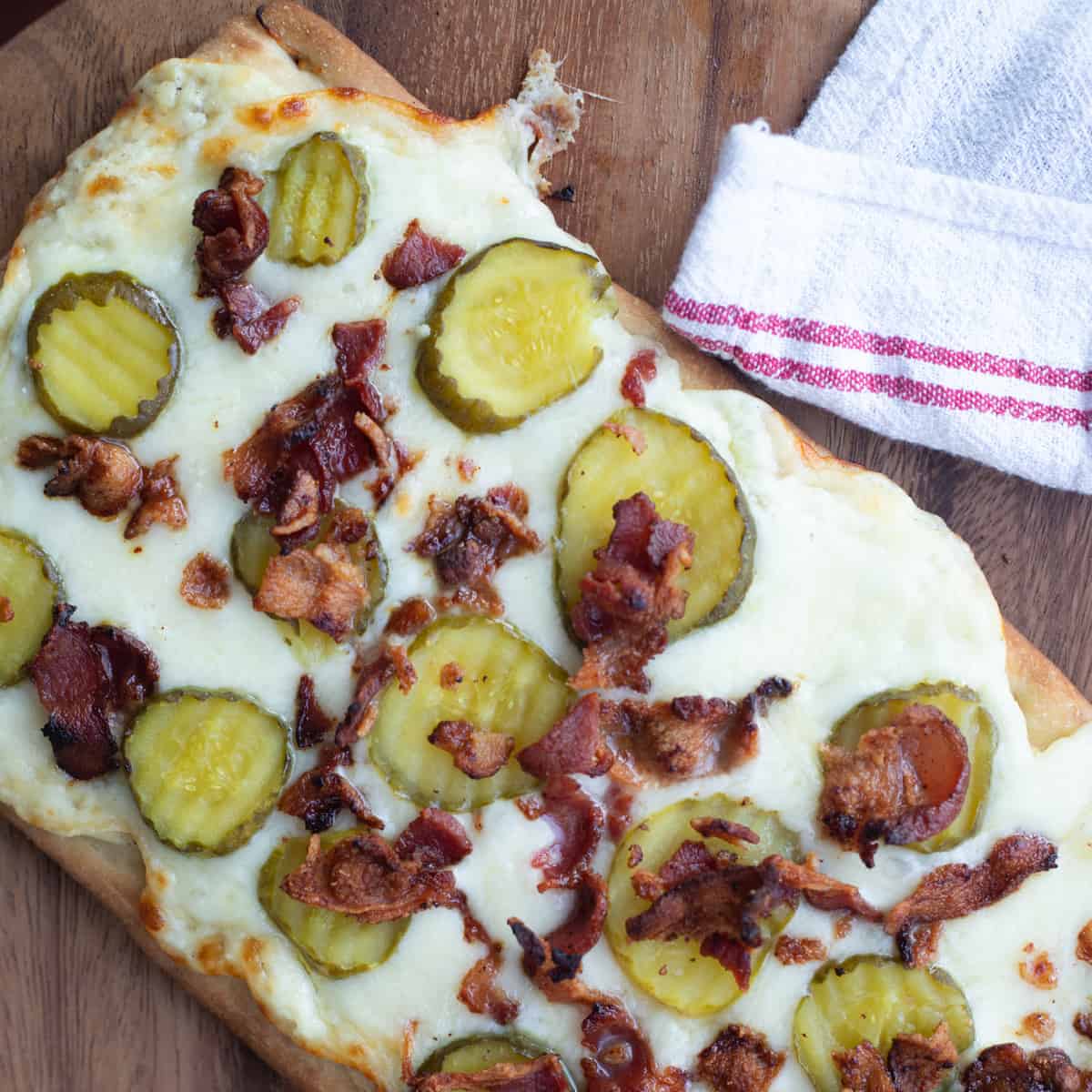 Pickle flatbread pizza on a cutting board.