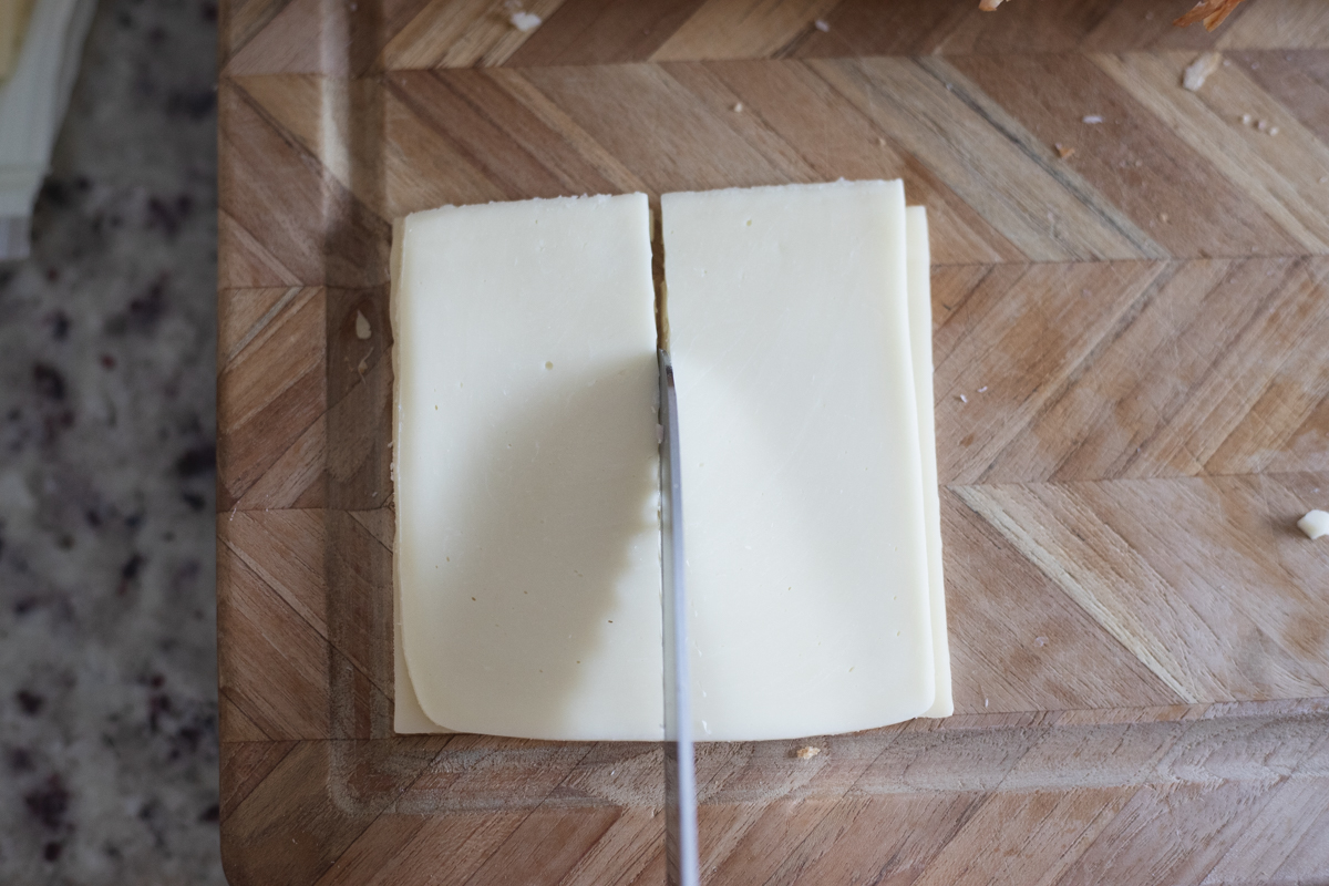 A slice of cheese being cut in half. 