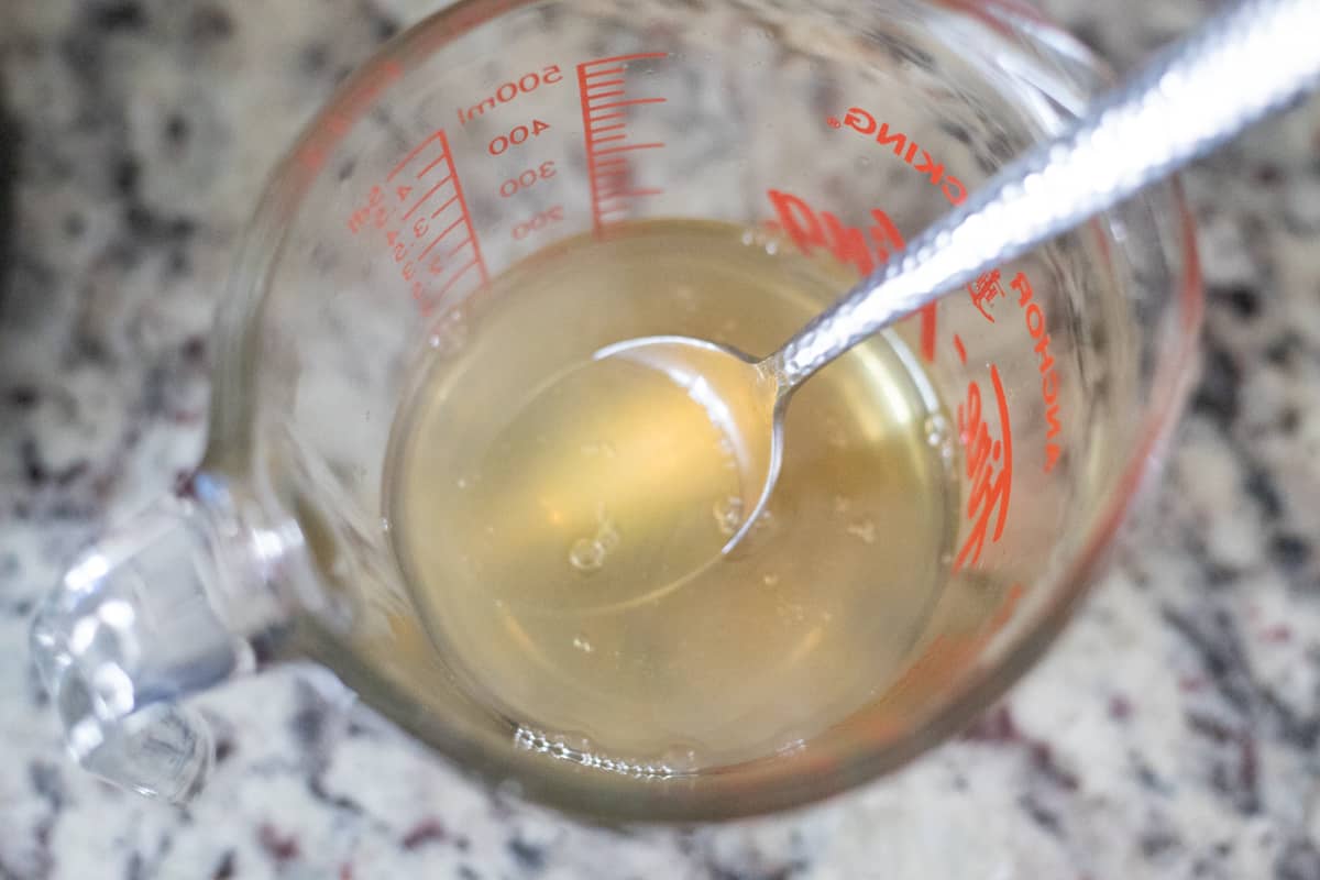 Honey and boiling water combined in a glass mixing bowl. 
