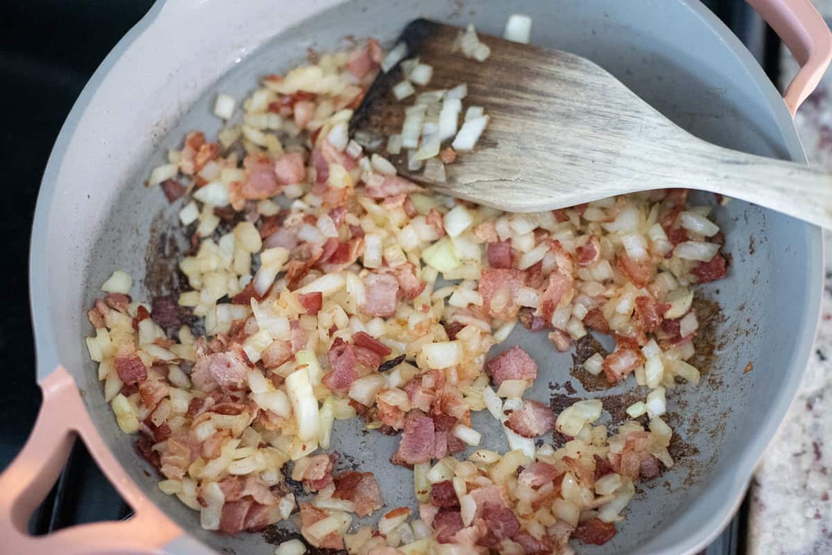 Bacon, onion, and garlic cooking in a pan. 