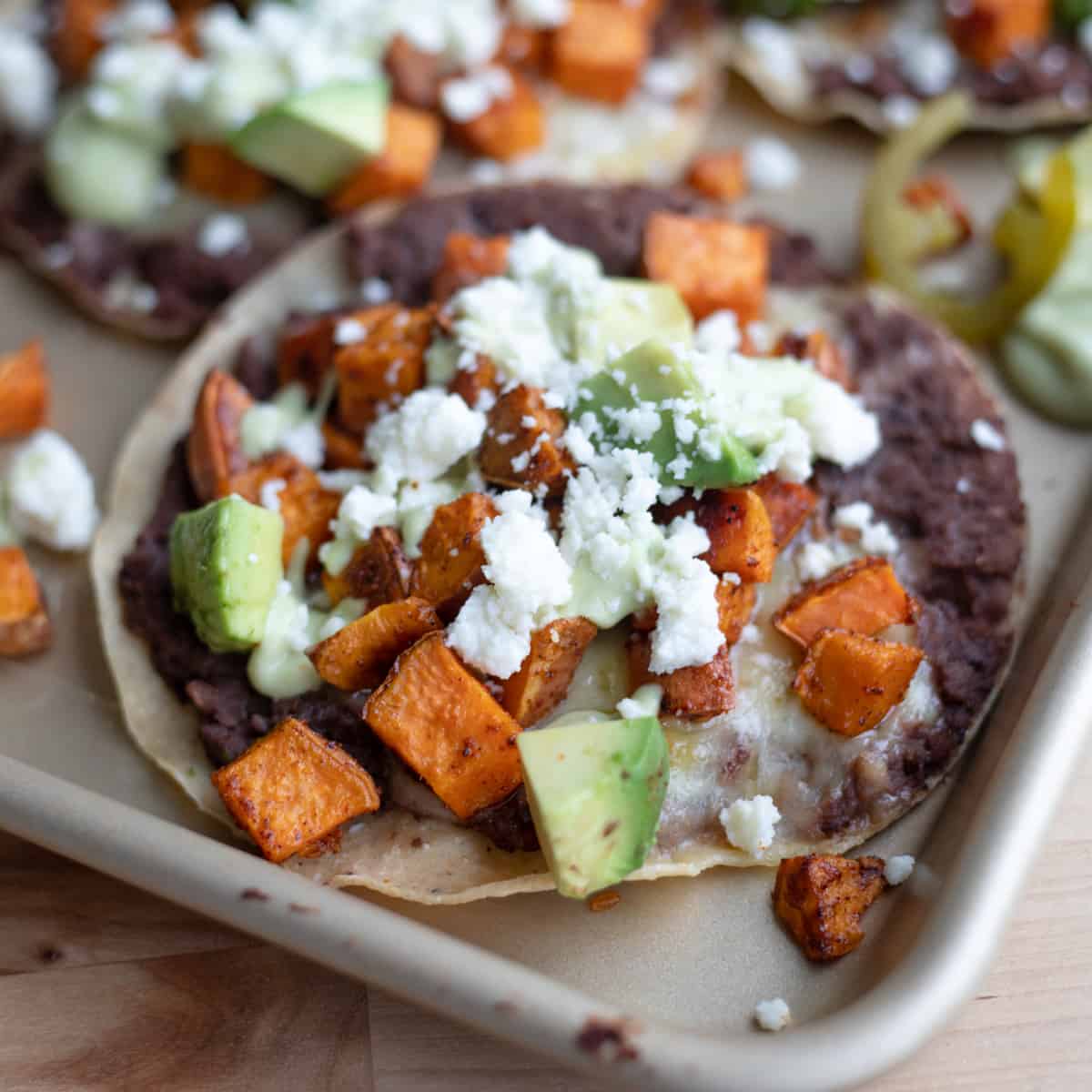 A sweet potato vegetarian tostada topped with cheese, avocado, and jalapeños. 