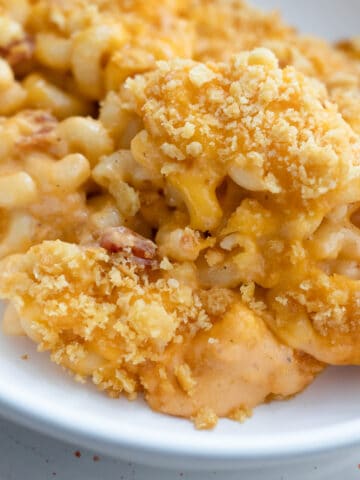 An up close view of baked bacon macaroni and cheese in a serving bowl.