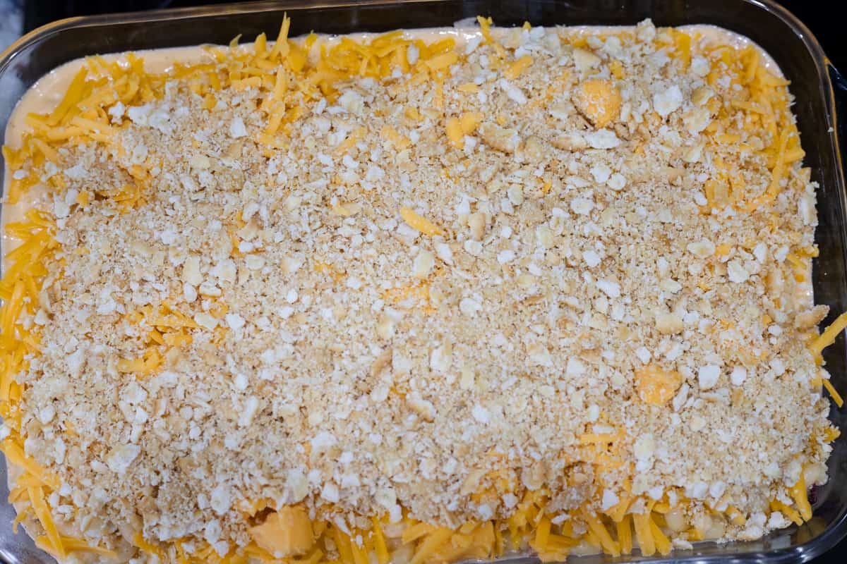 Macaroni and cheese, shredded cheddar, and broken Ritz crackers layered in a casserole dish. 
