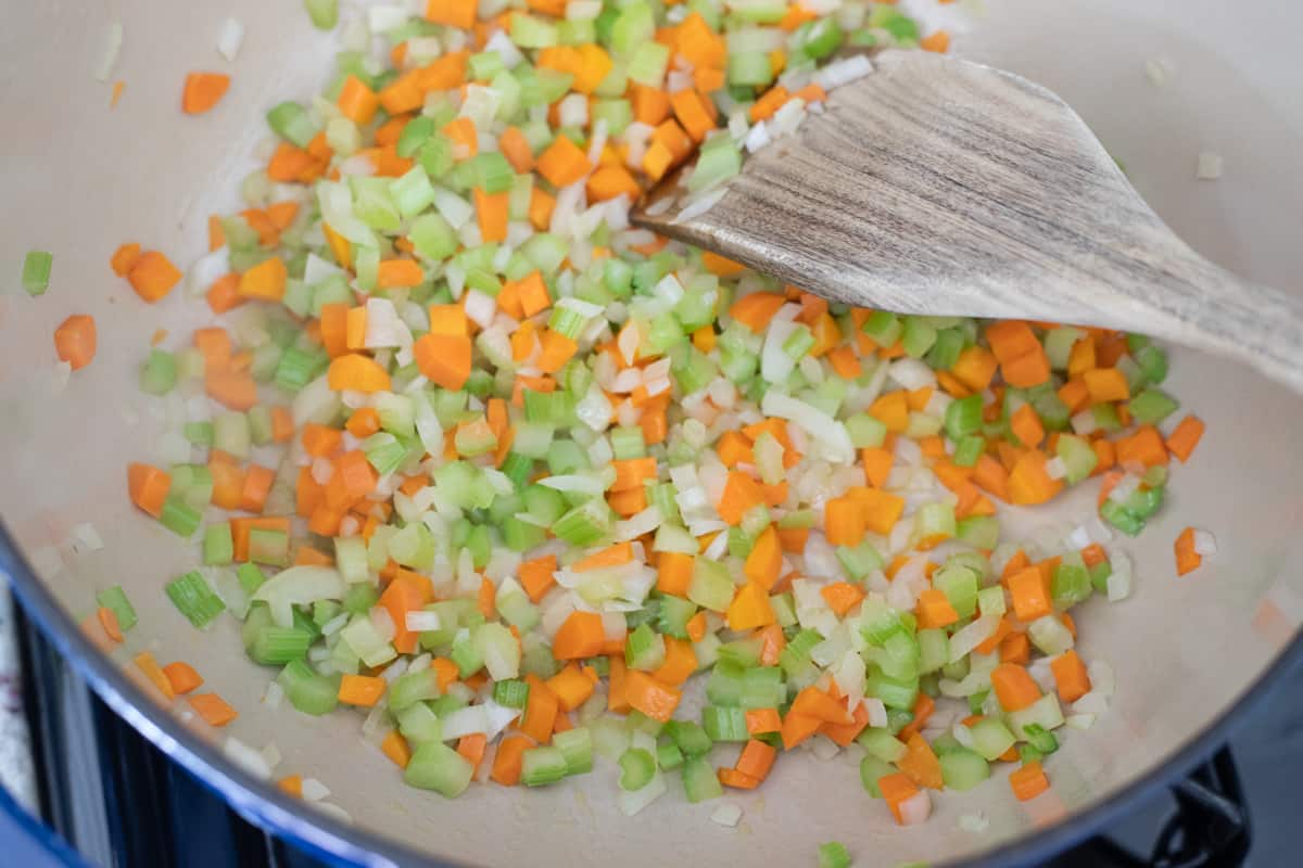 Onions, carrots, and celery cooking in a pot. 