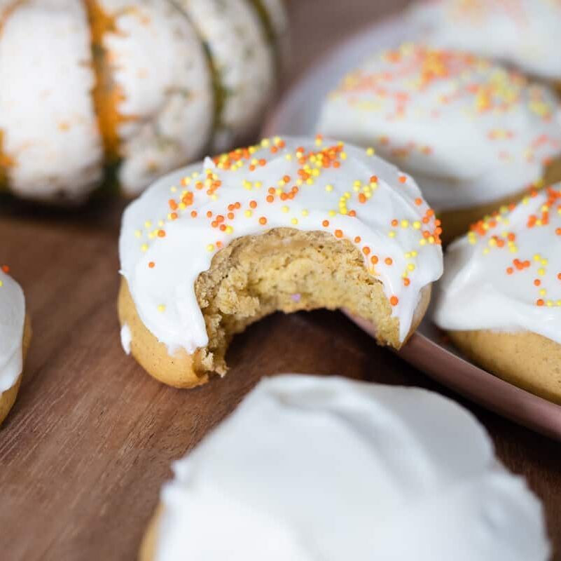 A bite out of a soft frosted pumpkin cookie. 