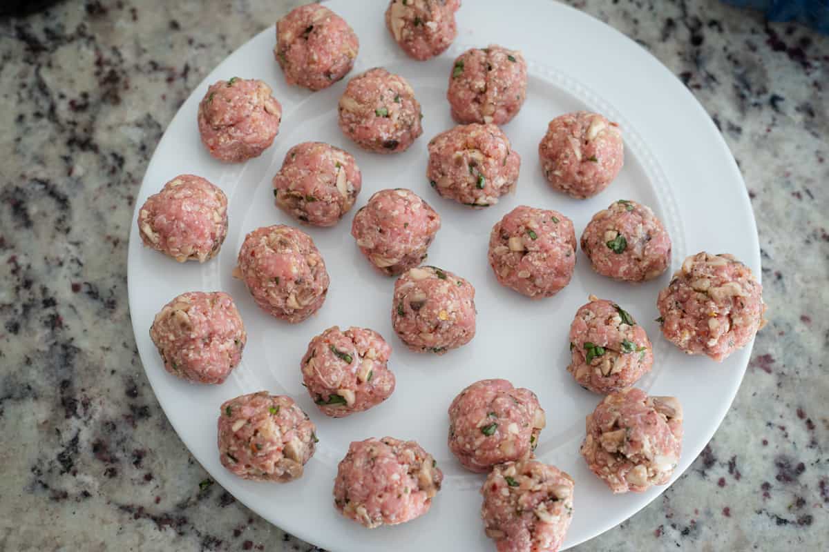 Shaped raw meatballs on a plate. 