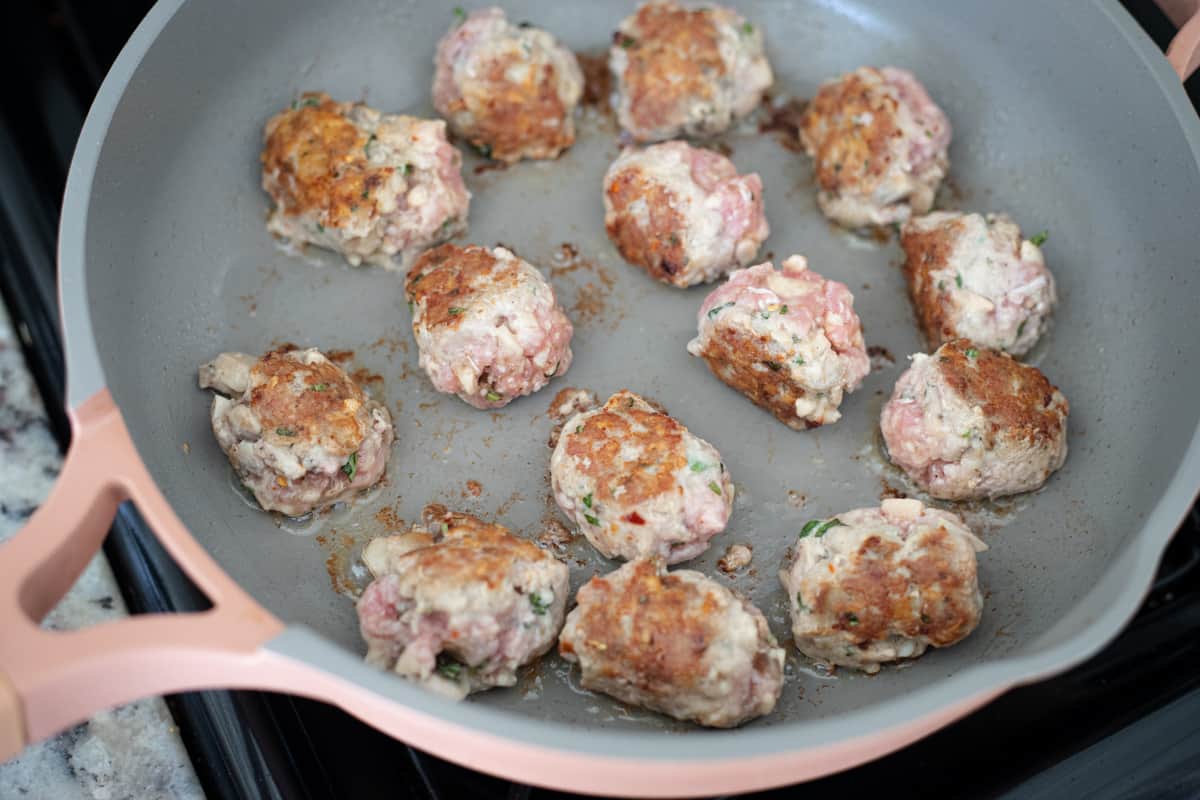 Meatballs searing in a pan. 