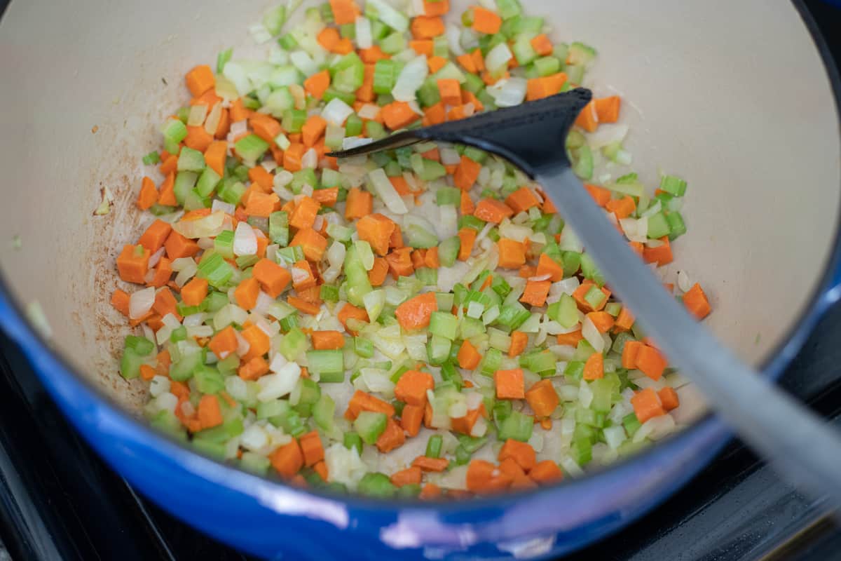 Onions, carrots, and celery cooking in a dutch oven. 
