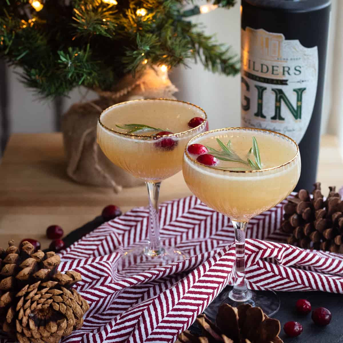 Two pear gin cocktails in front of a Christmas tree. 