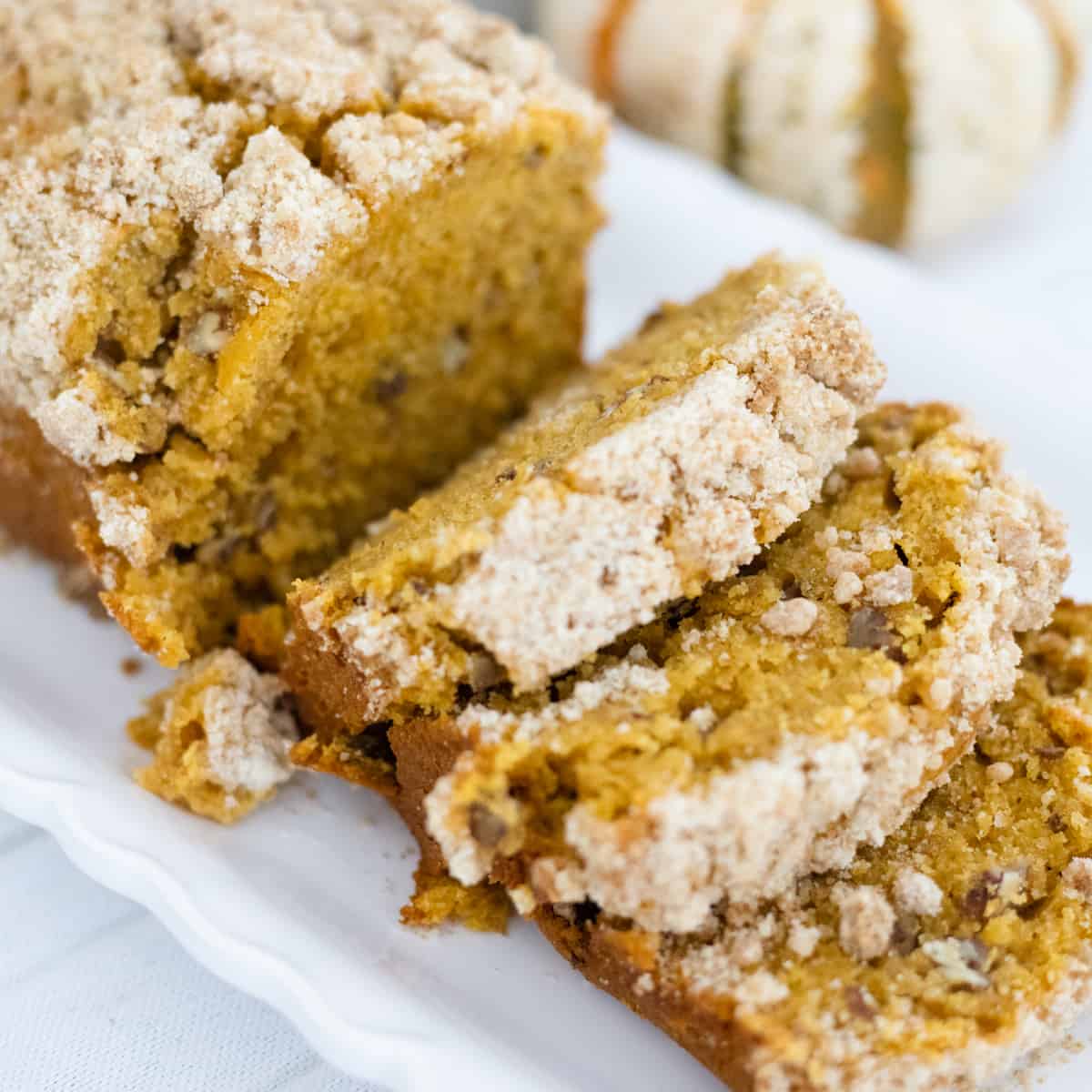 Pumpkin bread with streusel topping sliced on a serving platter.