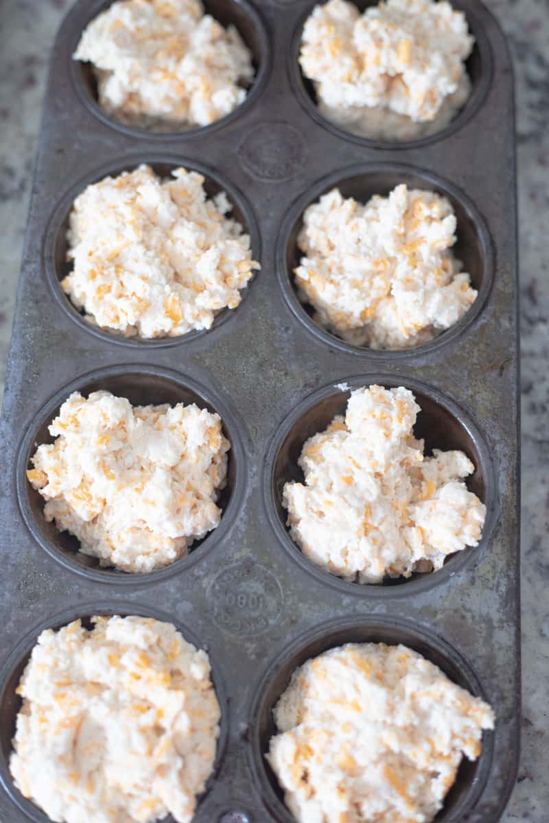 Bread dough in muffin tins. The dough is filled to the top of the tin. 