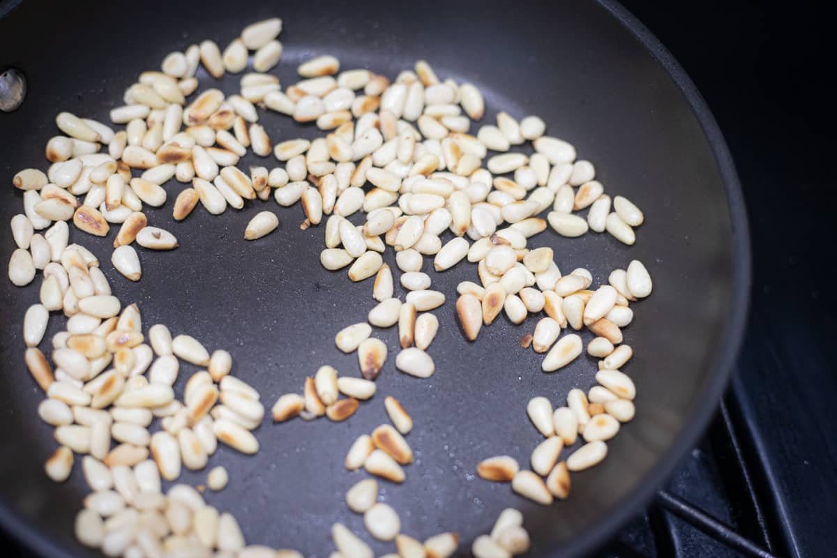 Pine nuts toasting in a pan. 