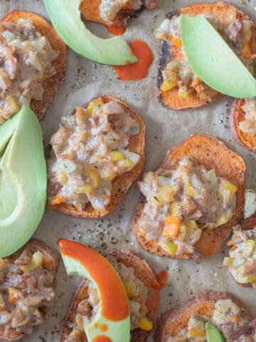 Sweet potato slices topped with a baked tuna mixture, avocado, and hot sauce.