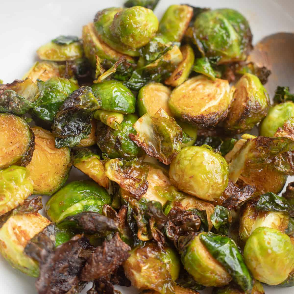 A close up of crispy air fryer BBQ brussels sprouts in a bowl. 