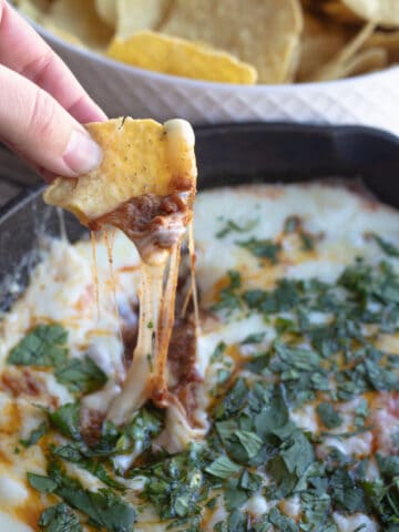 A chip being dipped into queso fundido with chorizo.