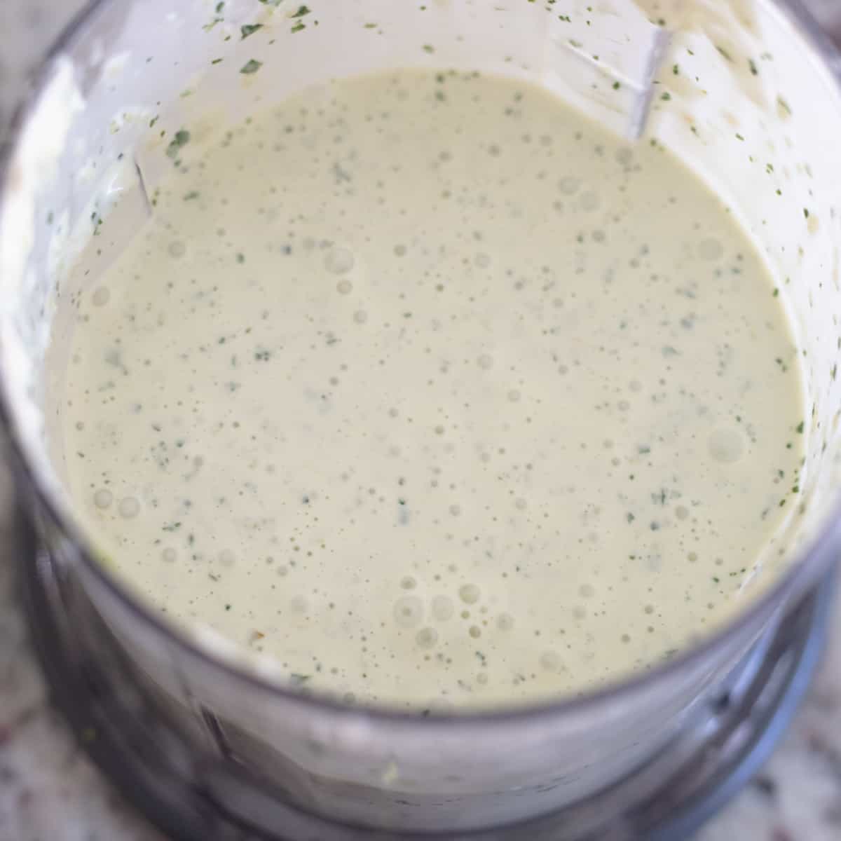 Mixed up sauce in a food processor. It's light green in color. 