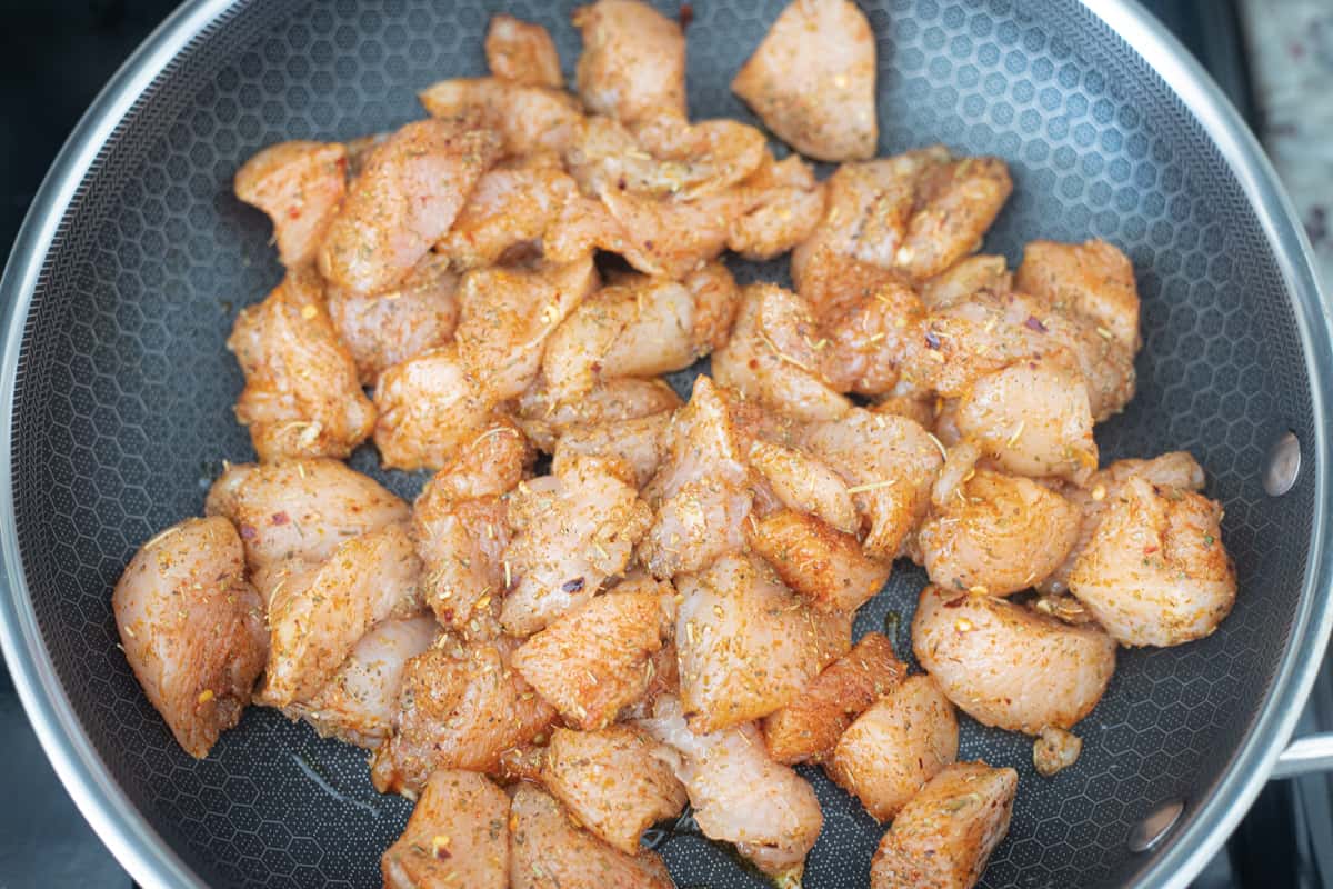 Raw chicken cooking in a pan. 