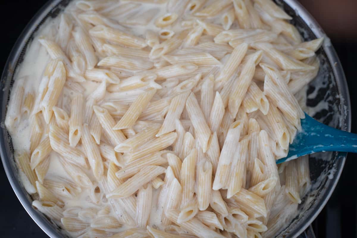 Penne in a cream sauce in a saucepan.