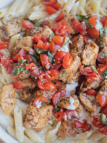 Pasta topped with chicken and bruschetta.