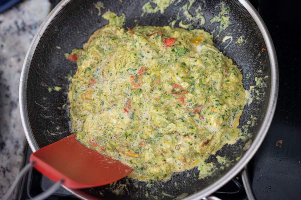Scrambled pesto eggs cooking in a pan. 