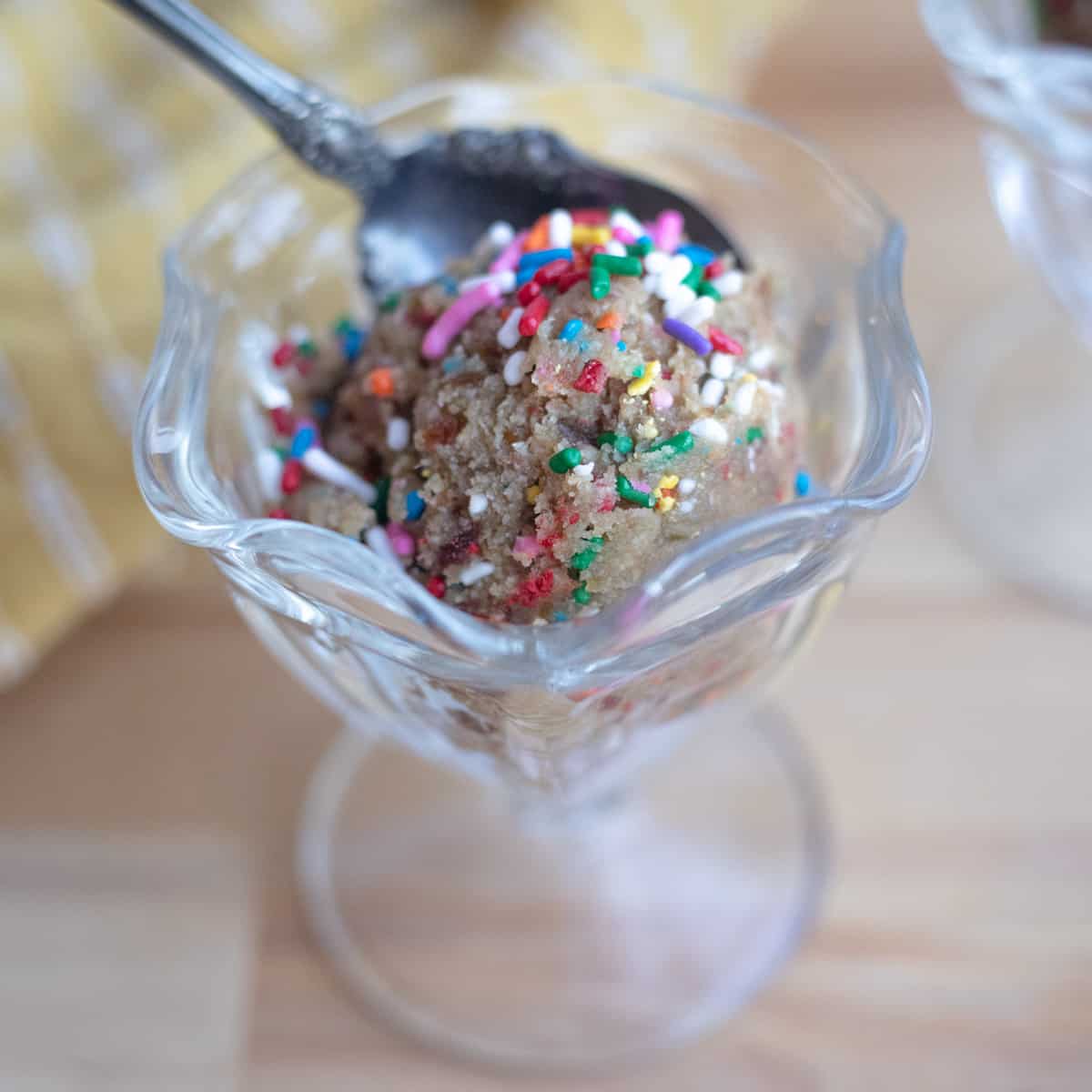 Edible sugar cookie dough in a serving dish with a spoon. 