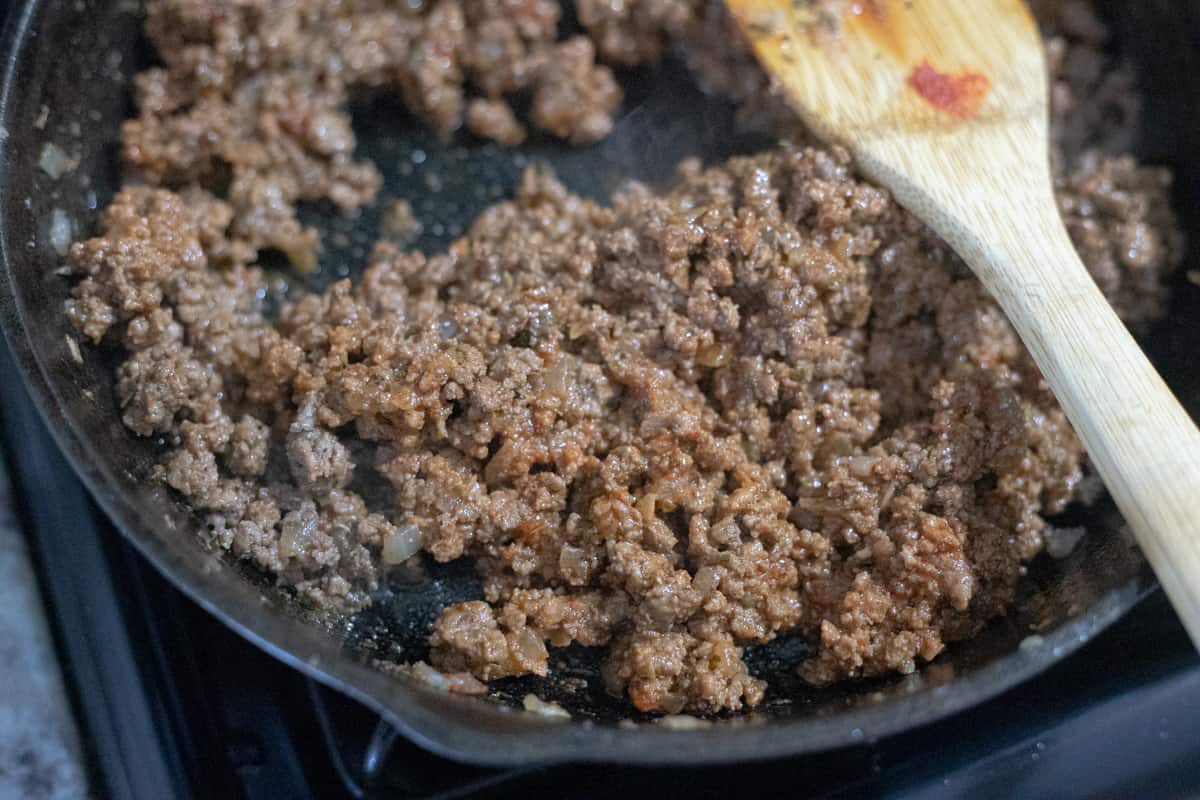 Ground beef mixed with tomato paste cooking in a pan. 