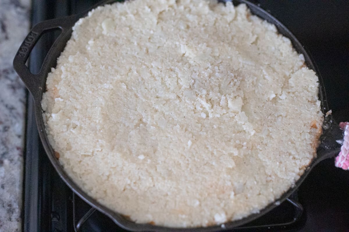 A cast-iron pan filled with cottage pie filling and topped with mashed cauliflower.