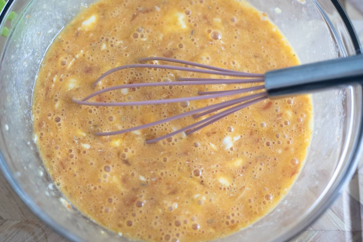 Whisked eggs and cheese in a bowl. 