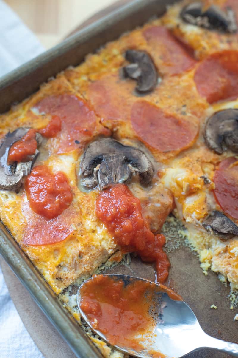 Sheet pan eggs topped with pizza ingredients like pepperoni and marinara sauce.