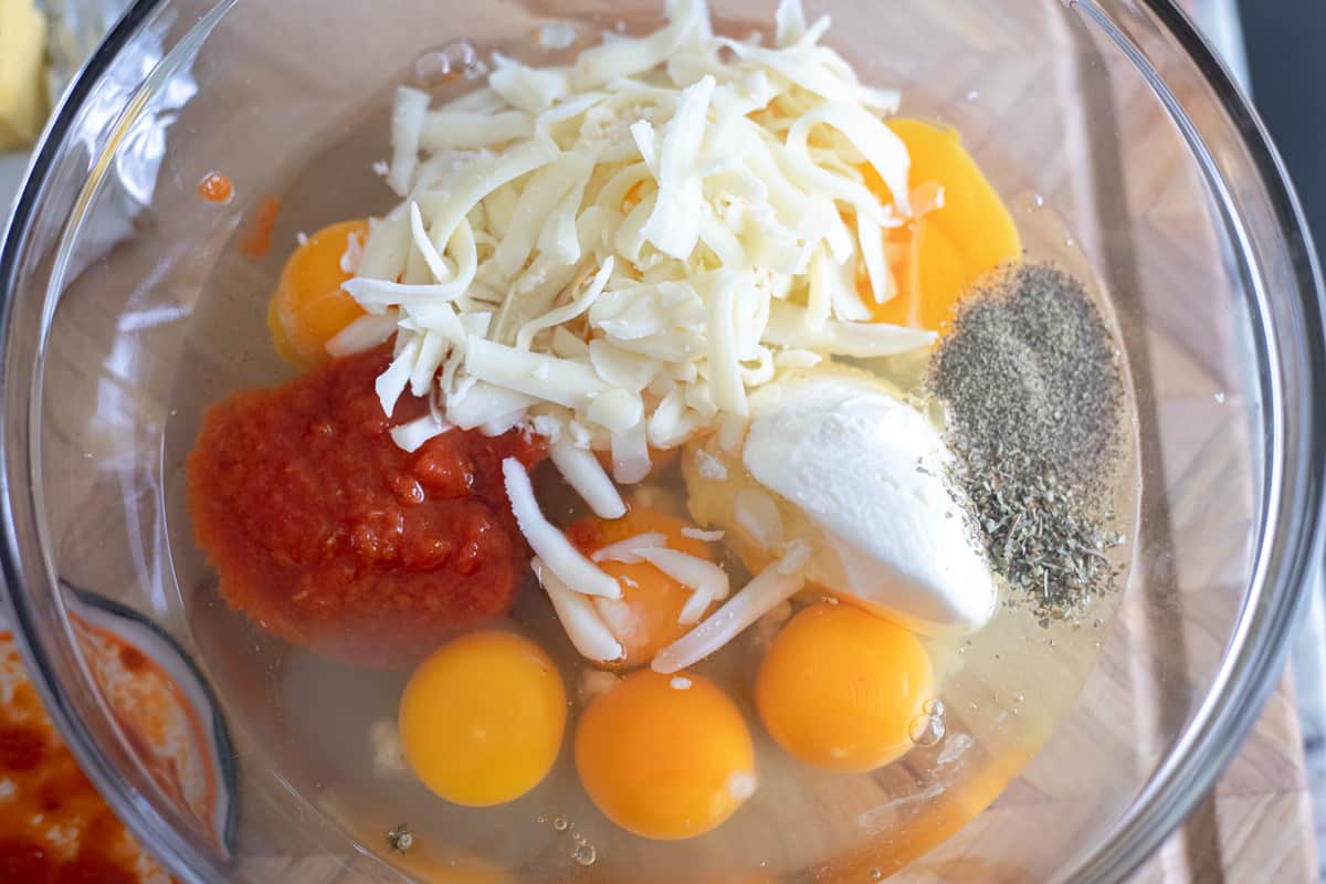 Eggs, cheese, marinara sauce, and seasonings in a mixing bowl. 