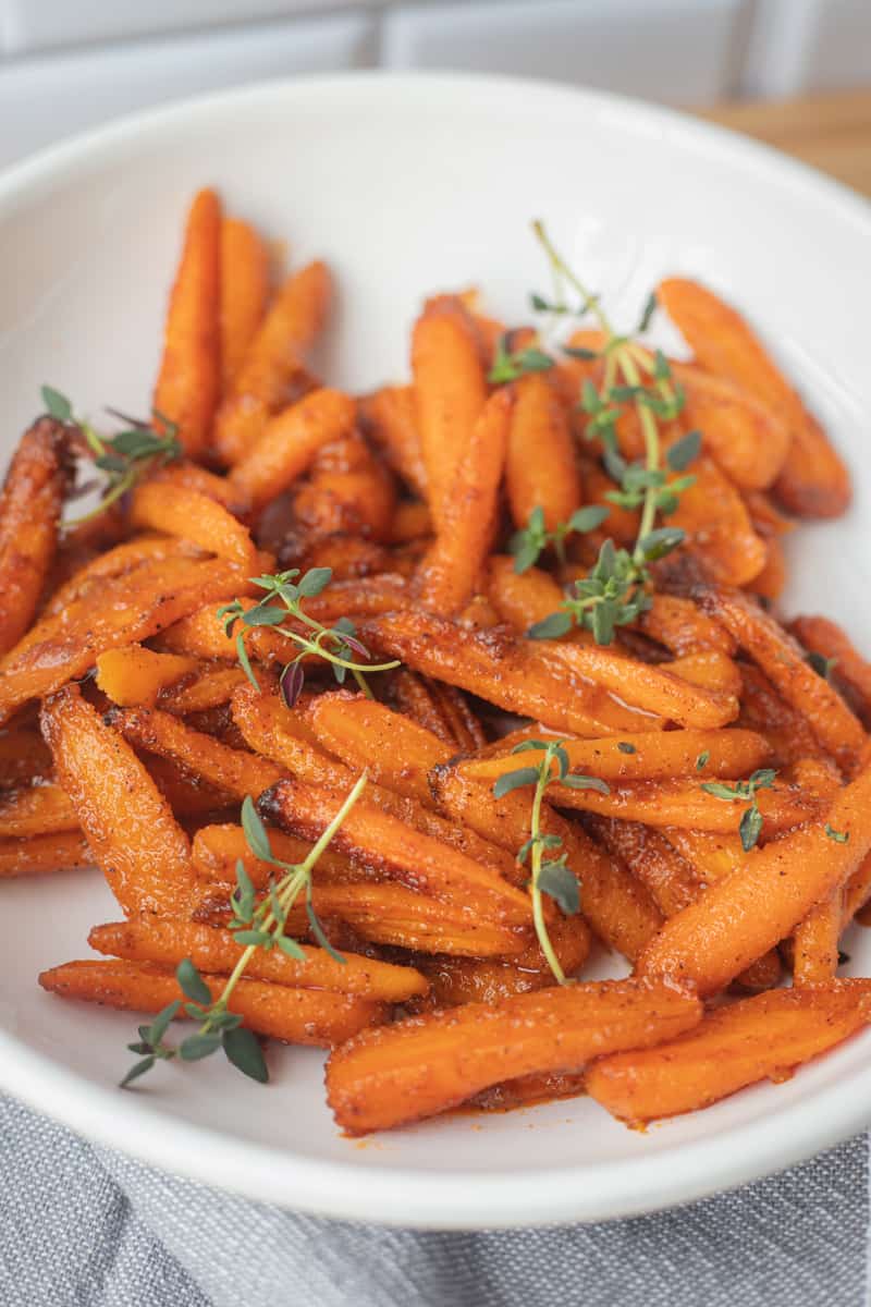 Air fryer baby carrots in a serving bowl topped with green garnish. 