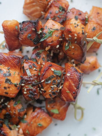 A plate of air fryer marinated salmon bites on skewers.