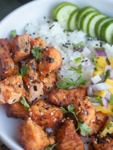 Air fryer salmon bites in a bowl with rice and mango salsa.