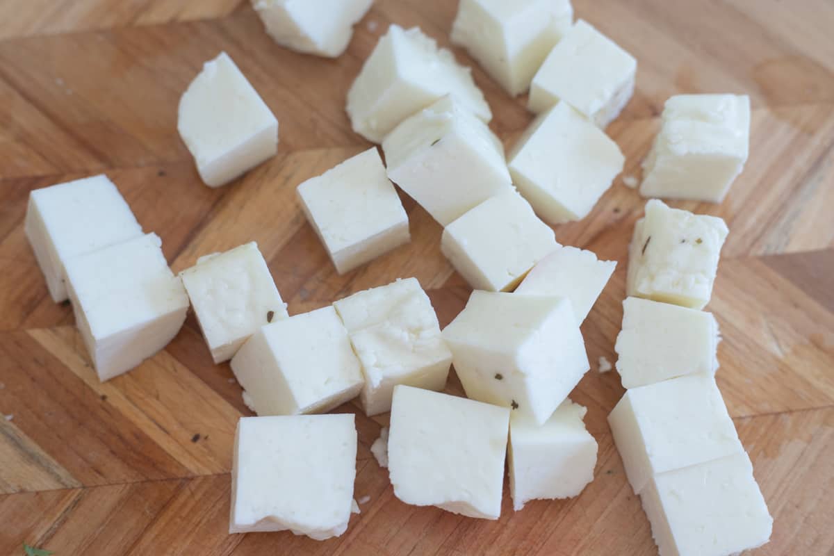 Halloumi cheese cut into cubes on a cutting board. 