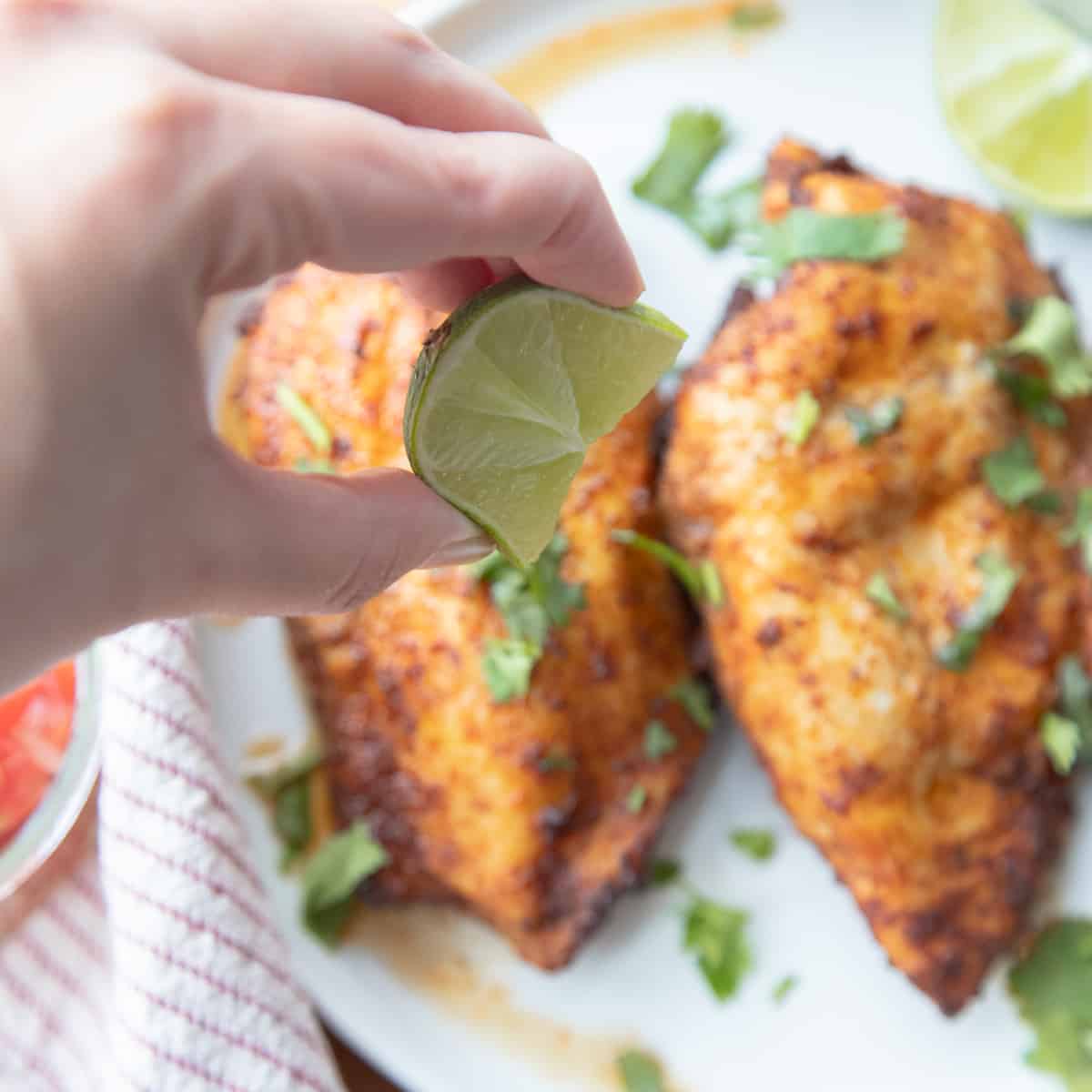 Lime being squeezed on two chicken breasts. 