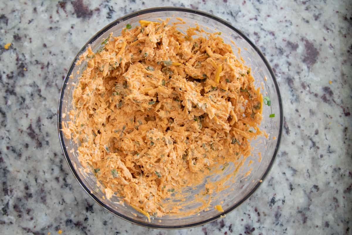 Buffalo chicken egg roll filling in a mixing bowl. It is orange in color and the ingredients are well mixed. 